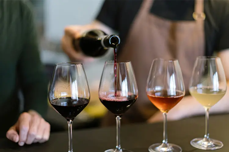 várias taças de vinhos sendo preparadas para prova de diferentes variedades da bebida