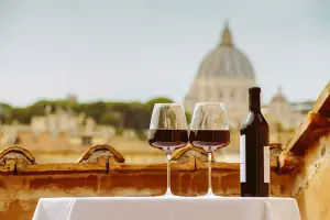 taças de vinho com vinho tinto e garrafa em me mesa de terraço com cúpula oa fundo