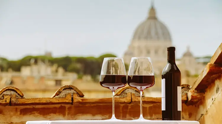 taças de vinho com vinho tinto e garrafa em me mesa de terraço com cúpula oa fundo