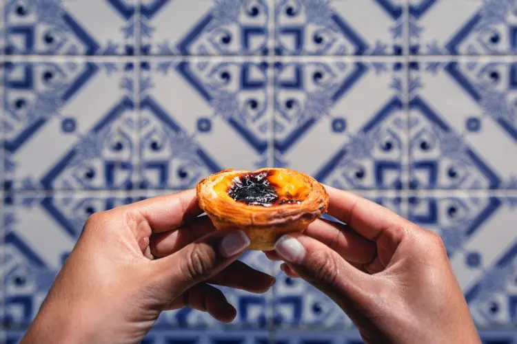 Mulher segurando pastel de Nata