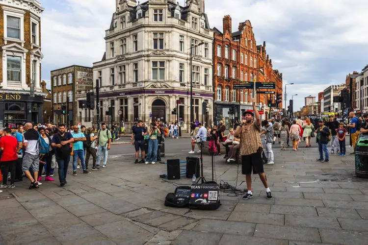 Cantor se apresentando nas ruas de Camden town em dia nublado