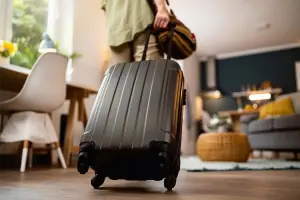 Mulher com mala entrando em casa alugada no Airbnb