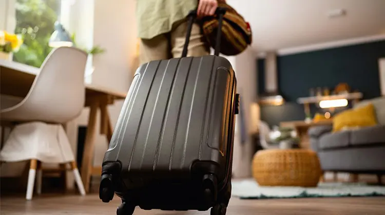 Mulher com mala entrando em casa alugada no Airbnb