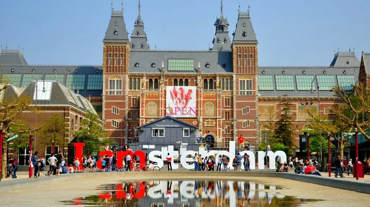 Placa I Amsterdam em frente a construção imponente