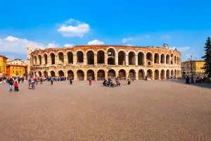 Turistas em frente à Arena de Verona em dia de céu azul na cidade romântica.