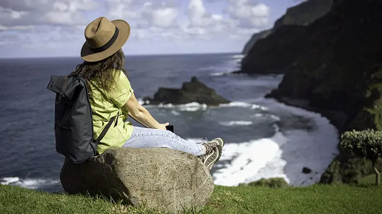 Mulher relaxa no alto de montanha na Europa, depois de contratar um seguro viagem da Assist Card