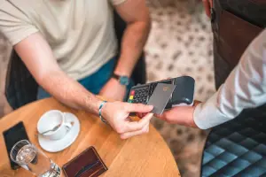 Homem pagando sua conta em um restaurante usando cartão por aproximação.