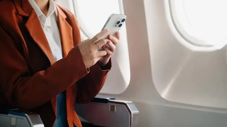 Mulher no avião usa celular com chip internet ilimitada internacional