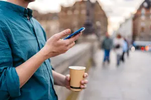 homem segura celular com chip de internet na França e café na rua