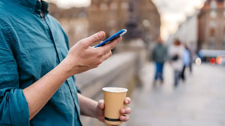 homem segura celular com chip de internet na França e café na rua