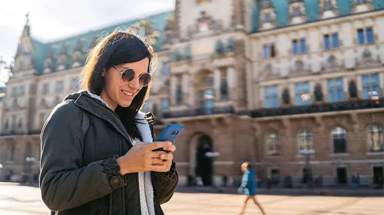 Mulher usando o celular enquanto viaja na Alemanha