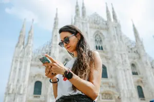 Mulher usando o celular em frente ao Duomo em Milão