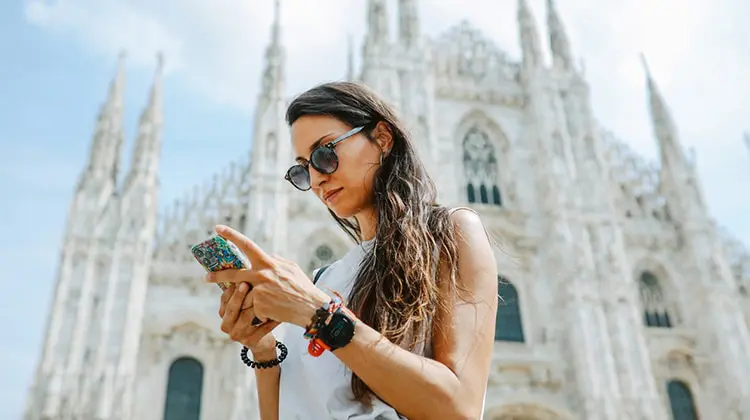 Mulher usando o celular em frente ao Duomo em Milão