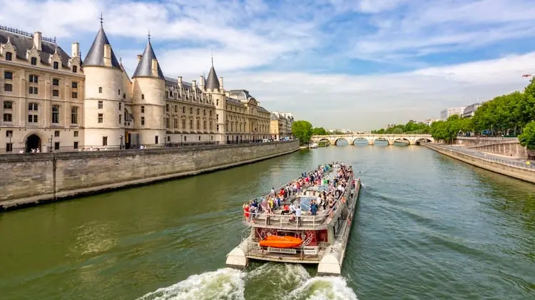 Rio Sena, em Paris, com um barco repleto de turistas, em dia nublado