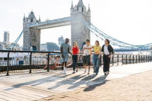 Amigos andando em Londres com Rio Tãmisa e a Tower Bridge ao fundo