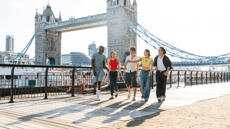 Amigos andando em Londres com Rio Tãmisa e a Tower Bridge ao fundo