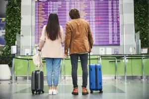 Casal olhando o painel de embarque no aeroporto.