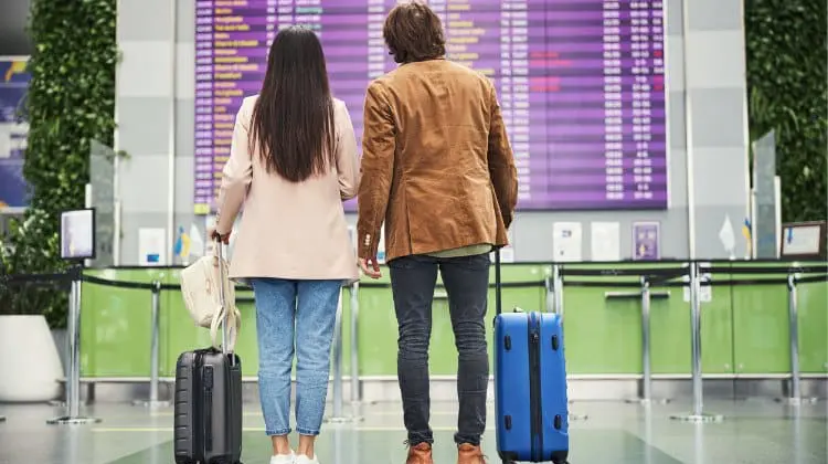 Casal olhando o painel de embarque no aeroporto.
