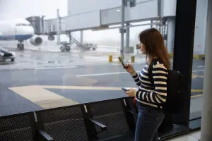 Mulher usando celular no aeroporto.