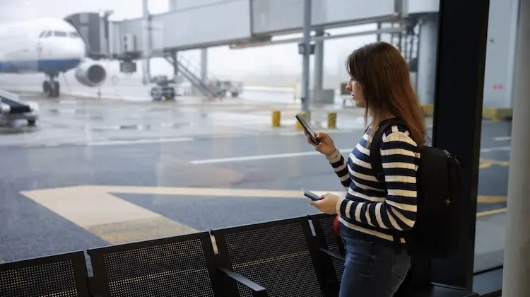 Mulher usando celular no aeroporto.