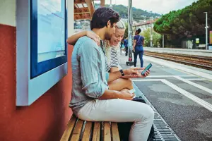 Casal usa celular em estação de trem na Europa