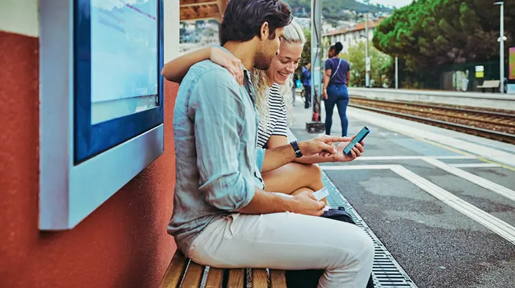 Casal usa celular em estação de trem na Europa