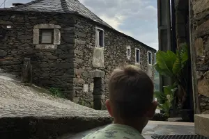 Menino olha para casa tradicional de pedra.