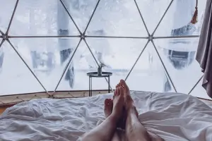 Casal deitado em cama em quarto de hotel que é uma bolha transparente
