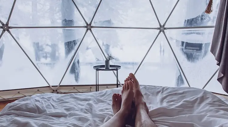 Casal deitado em cama em quarto de hotel que é uma bolha transparente