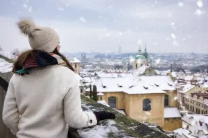 Mulher em inverno na Europa, olhando uma cidade coberta de neve.