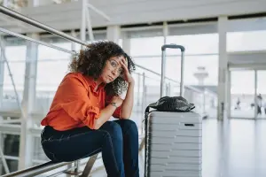 Mulher sentada em aeroporto, depois de cancelamento de voo.