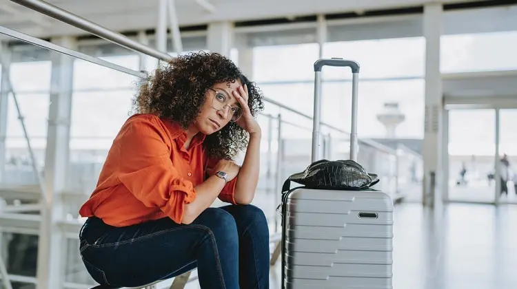 Mulher sentada em aeroporto, depois de cancelamento de voo.