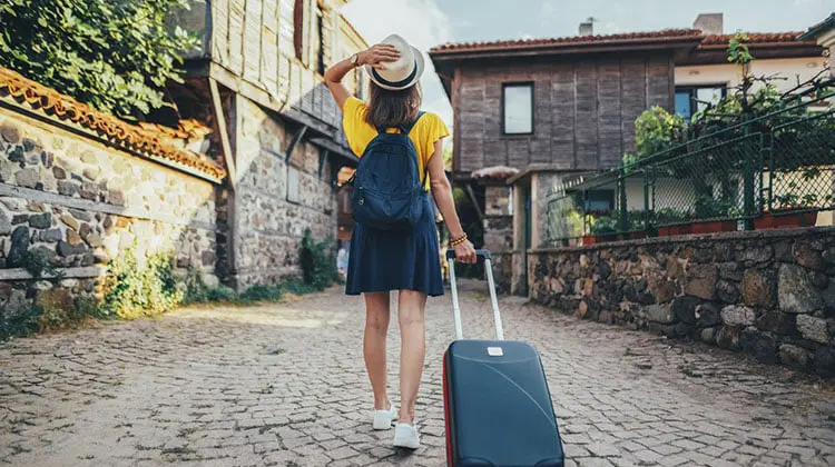 Turista passeando com mala de rodinhas que poderia ser uma mala Santino.