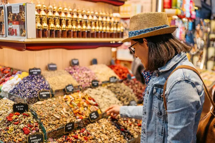 Uma mulher turista observa diferentes temperos no Bazar de Especiareis de Istambul