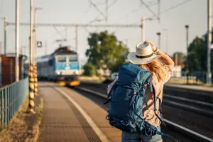 Mulher de costas na estação esperando o metrô com uma mochila
