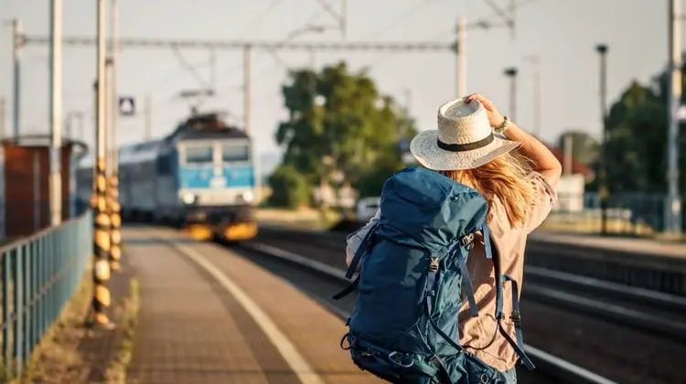Mulher de costas na estação esperando o metrô com uma mochila