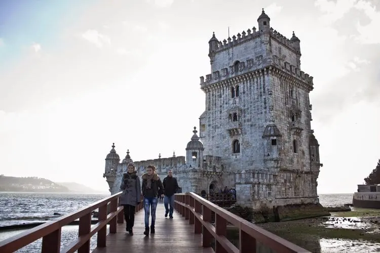 Pessoas andando na ponte em frente à Torre de Belém