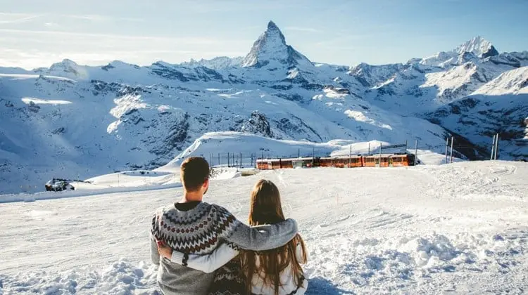 Casal admirando montanha famosa coberta de neve nos alpes suíços.