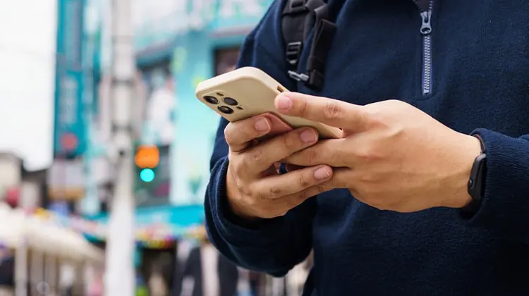 homem segura celular na rua durante viagem