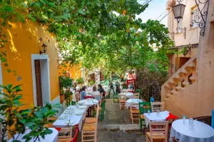 Mesas ao ar livre em rua arborizada de Atenas