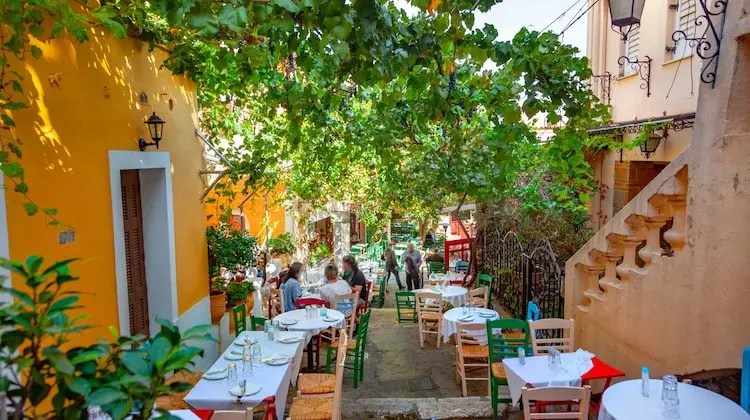 Mesas ao ar livre em rua arborizada de Atenas