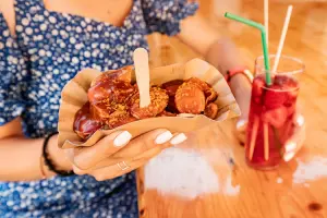 Mulher segurando currywurst e bebida onde comer em Berlim