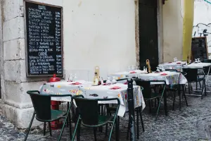 Mesas em área exterior e placa com com menu, onde comer em Lisboa
