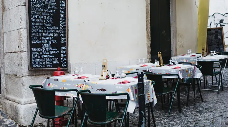 Mesas em área exterior e placa com com menu, onde comer em Lisboa