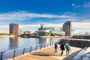 Pessoas caminhando próximo do rio de Manchester.