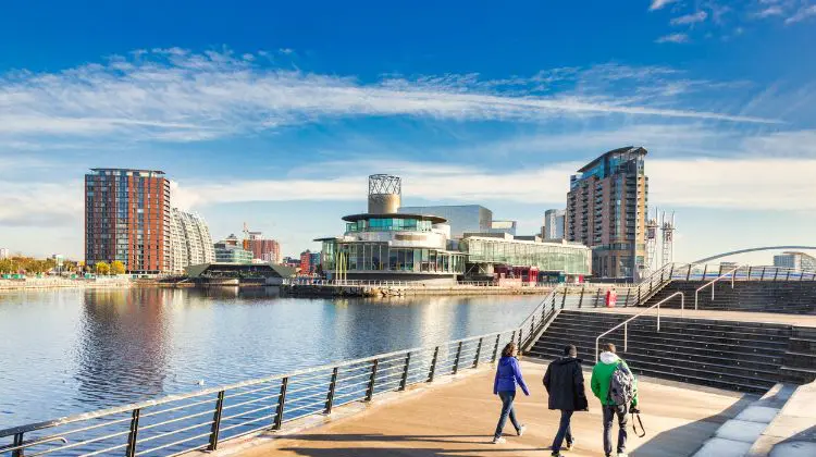 Pessoas caminhando próximo do rio de Manchester.