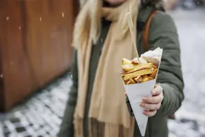 Mulher segura cone de batata frita, um dos pratos típicos da Bélgica