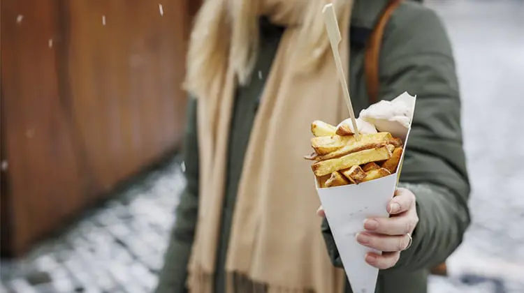 Mulher segura cone de batata frita, um dos pratos típicos da Bélgica