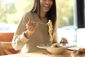 Mulher feliz comendo um prato de espaguete.