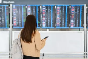 Jovem diante de painel no aeroporto